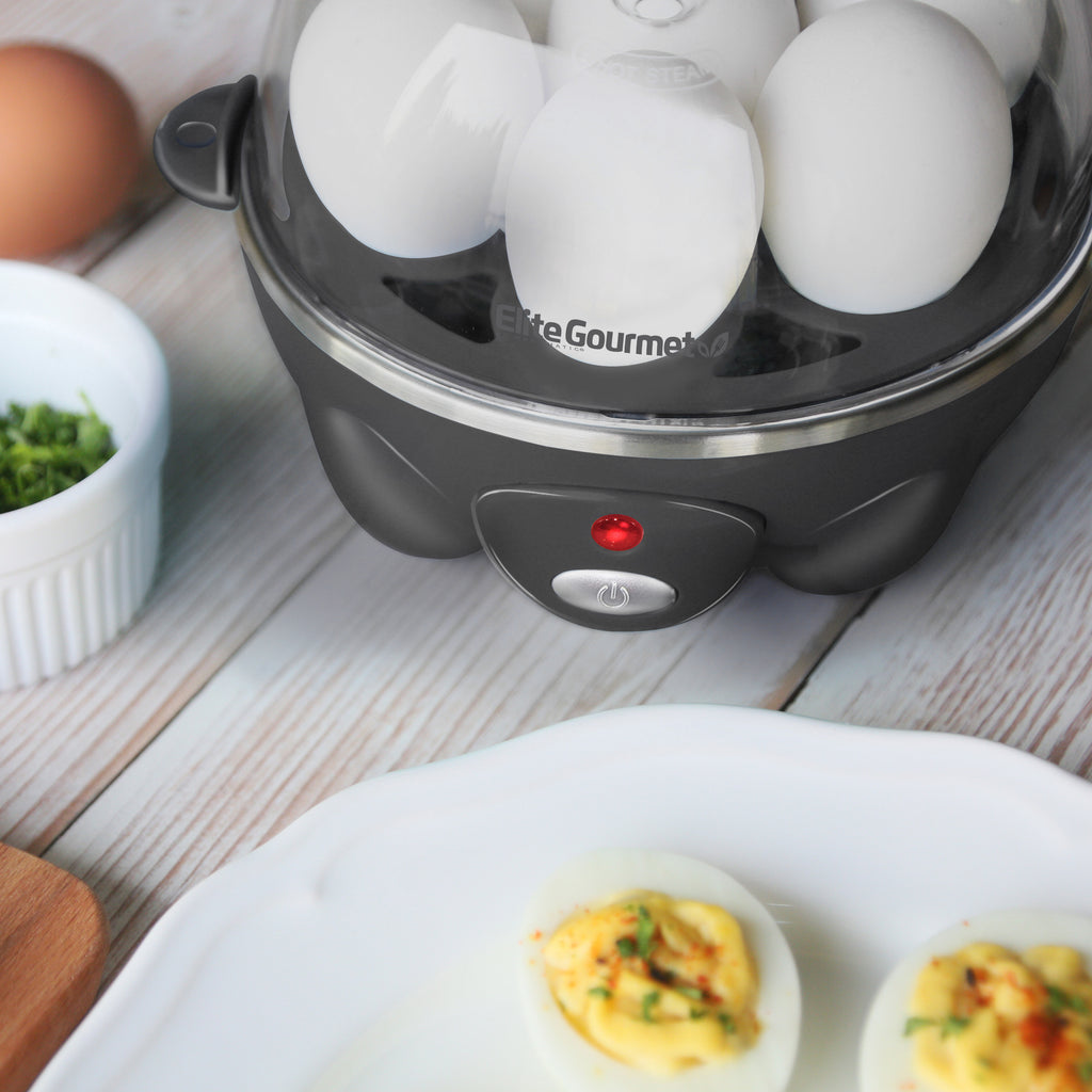 Egg cooker power indicator light is lit red. Plate of deviled eggs next to egg cooker.