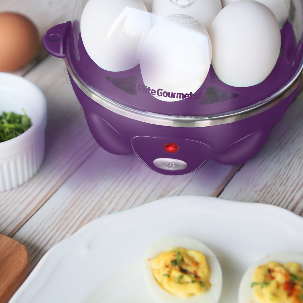 Egg cooker power indicator light is lit red. Plate of deviled eggs next to egg cooker.