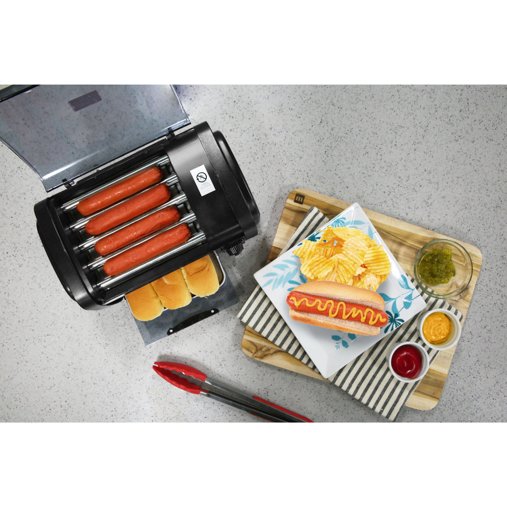 Overhead display of oven on kitchen counter next to a plate of hot dogs, chips and condiments.