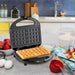 Waffle Maker set on kitchen counter next to ingredients and cooked waffles.